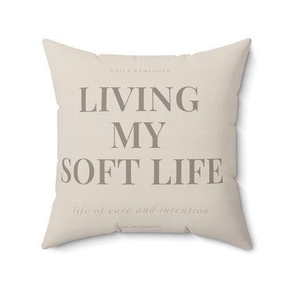 Beige pillow with text 'Living my soft life' on a white background