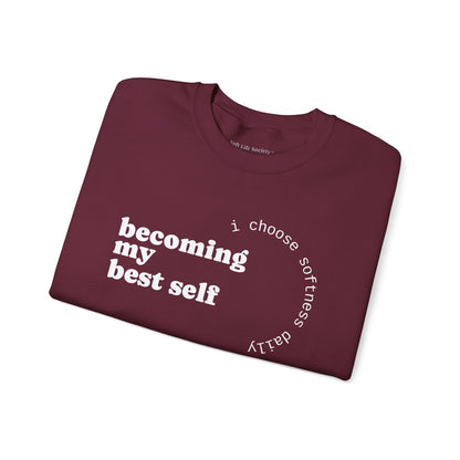 Maroon sweatshirt displayed flat showcasing the “becoming my best self” circular softness quote design.