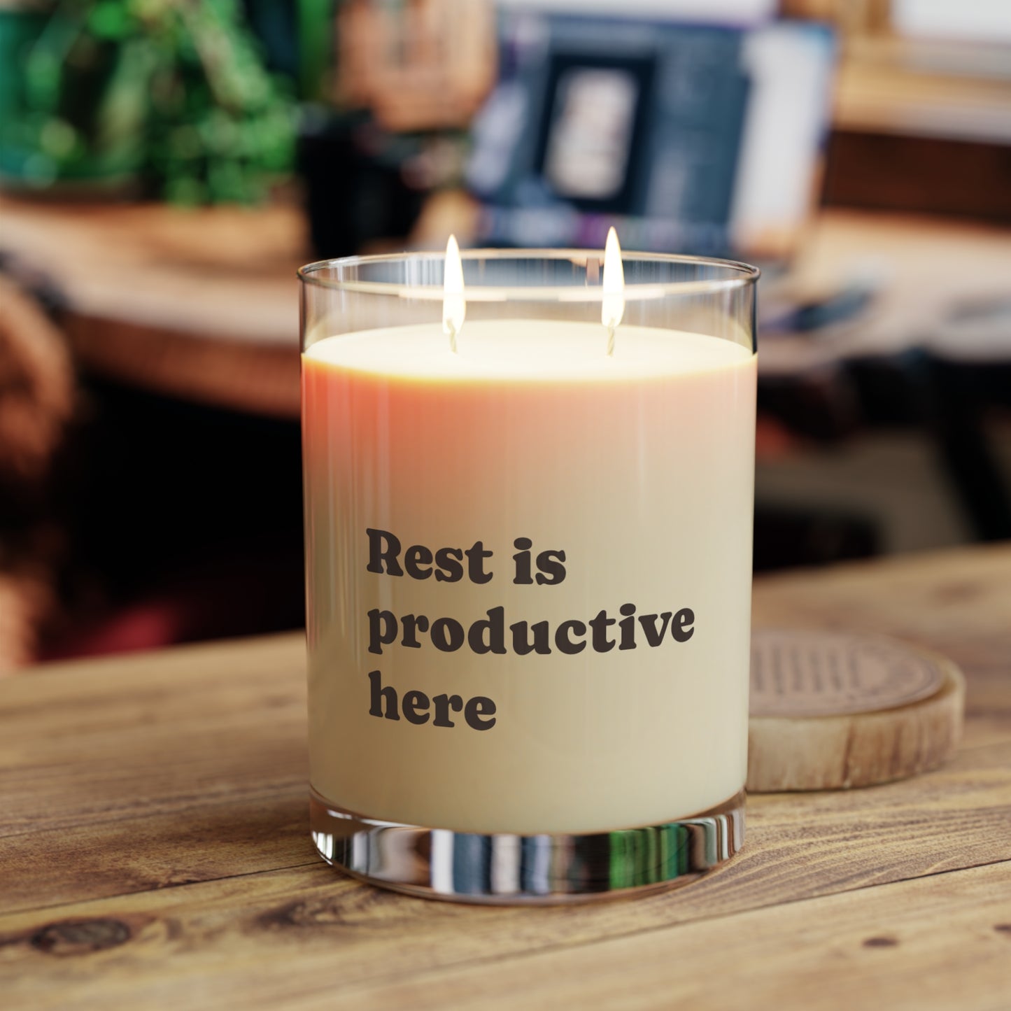 Candle with 'Rest is productive here' text on a wooden surface