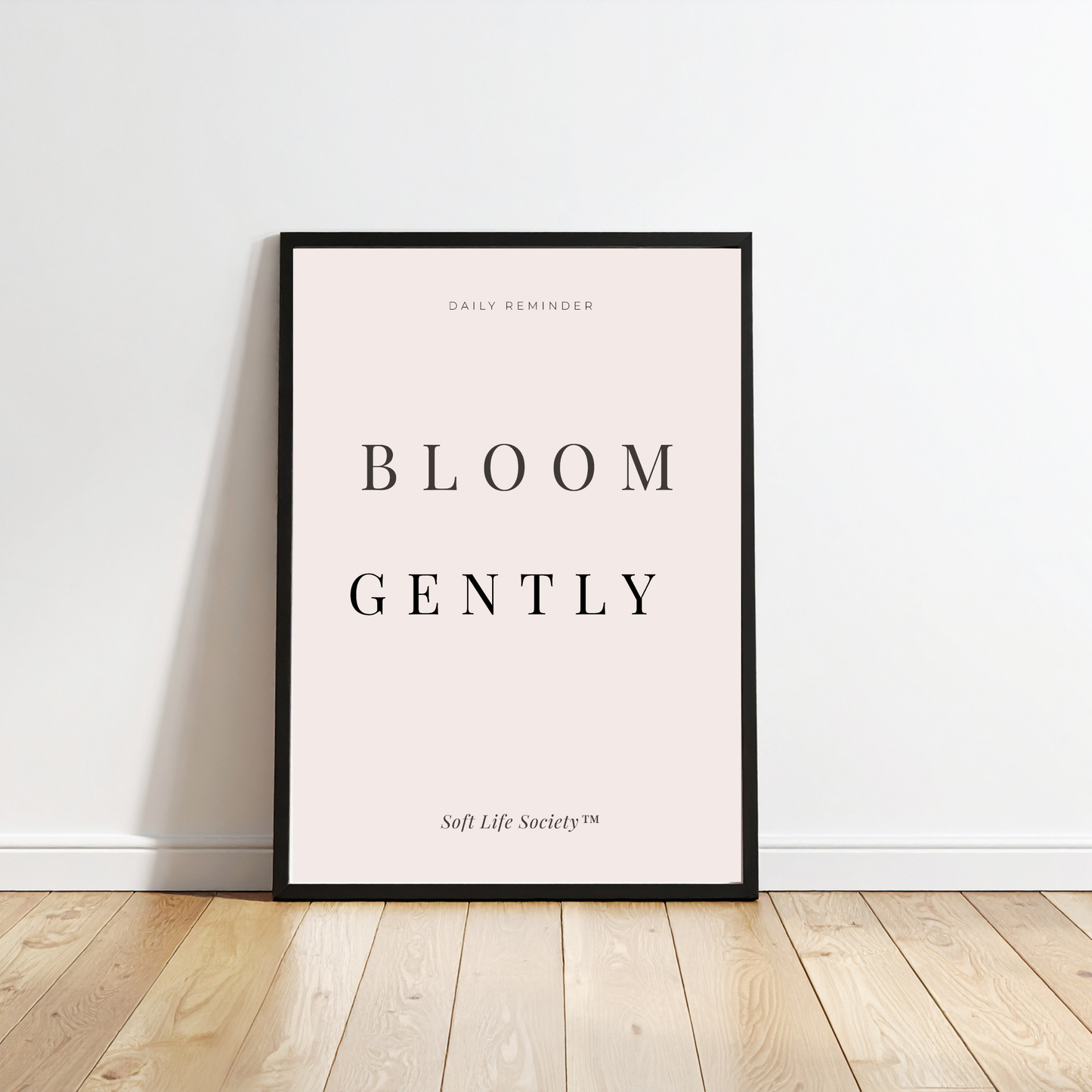 Framed print with 'Bloom Gently' text on a white wall.