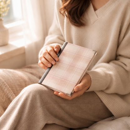 Person holding a plaid notebook in a cozy indoor setting
