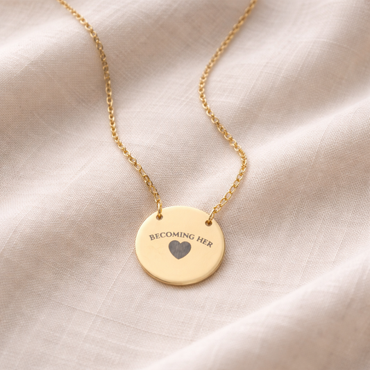 Gold necklace with a round pendant on a beige fabric background