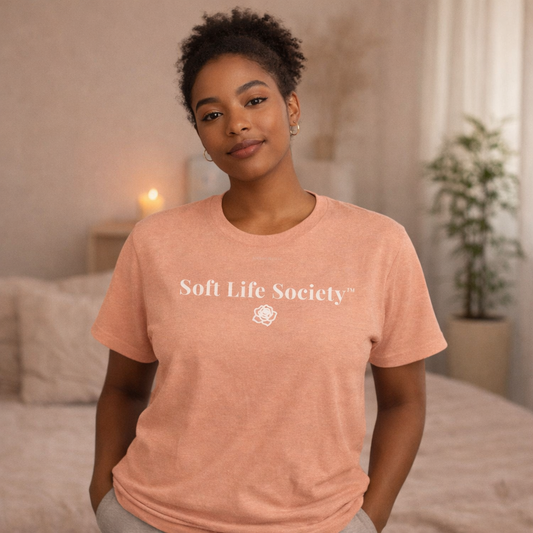 Woman wearing peach Soft Life Society t-shirt with white logo, cozy soft life outfit with coffee
