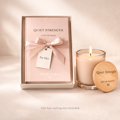 Candle and 'Quiet Strength' journal set on a light background
