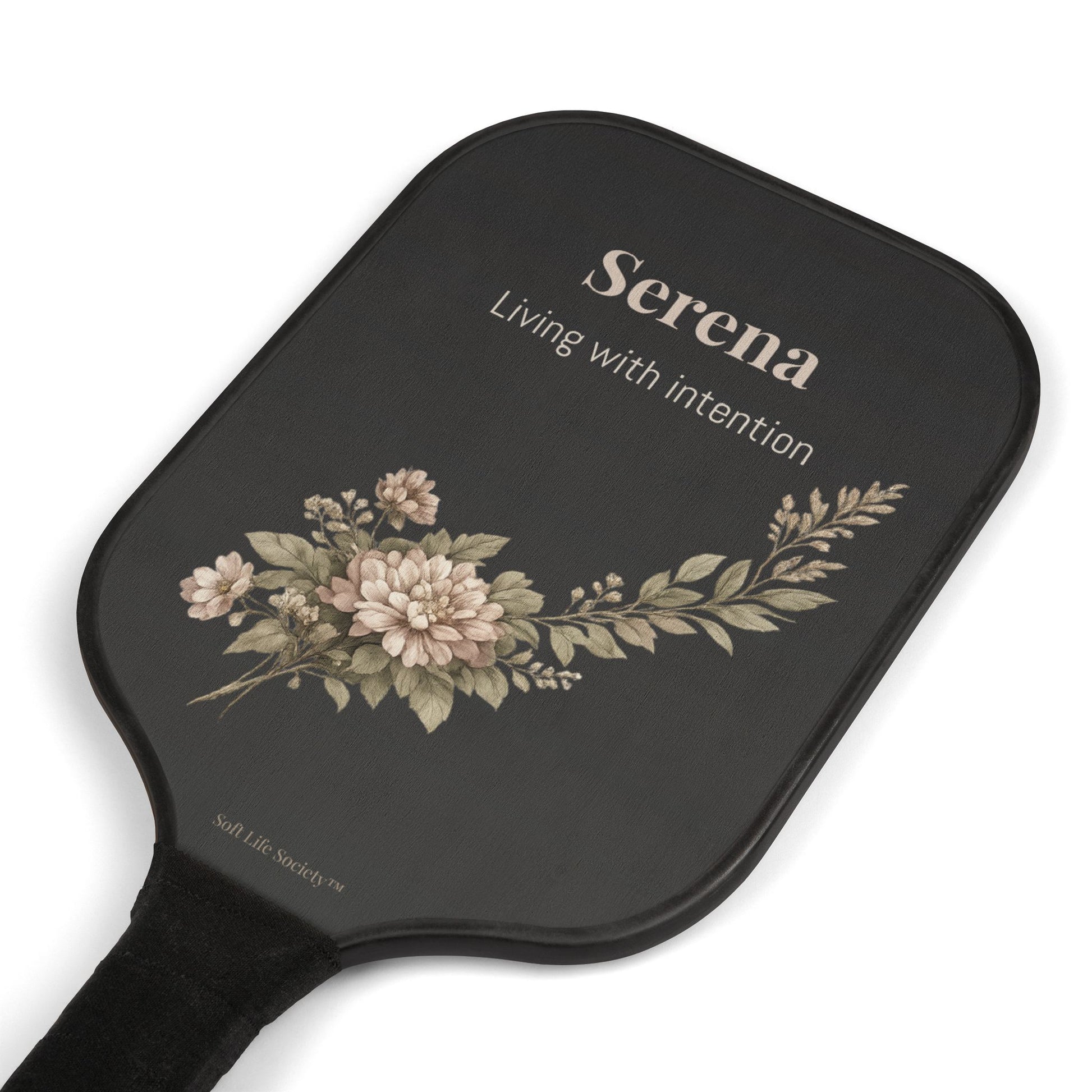 Black paddle with floral design and 'Serena' branding on a white background