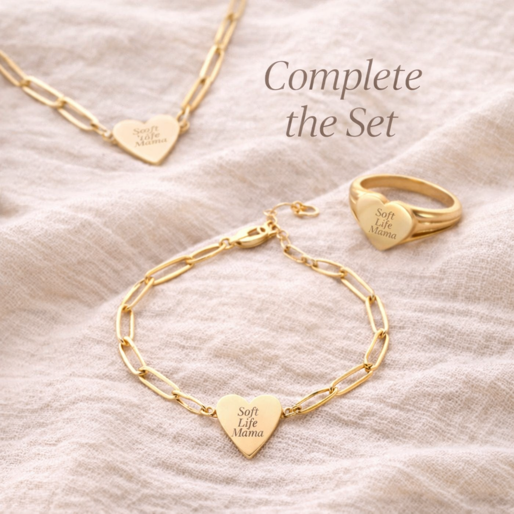 Gold bracelet and ring set with heart-shaped pendants on a beige fabric background