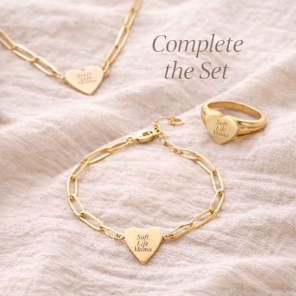 Gold bracelet and ring set with heart-shaped pendants on a beige fabric background