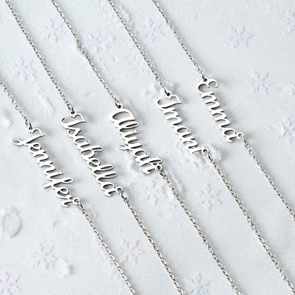 Assorted silver and gold personalized name necklaces arranged on soft white fabric for a flat-lay display.