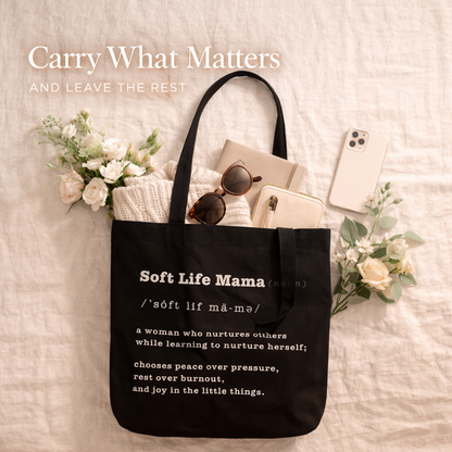Black tote bag with 'Soft Life Mama' definition text, filled with items on a light background.