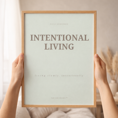 Framed print with 'Intentional Living' text held by hands against a neutral background