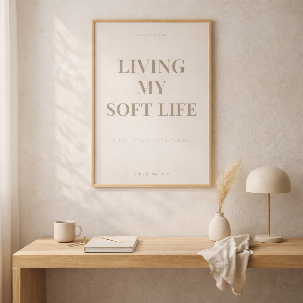 Framed poster with 'Living My Soft Life' text on a wall above a wooden desk.