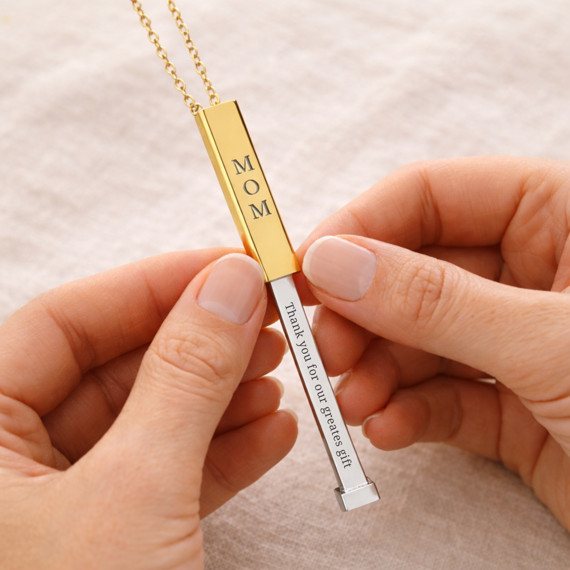 Personalized hidden message necklace for mom. Close-up of hands opening a gold bar necklace to reveal a hidden engraved message inside