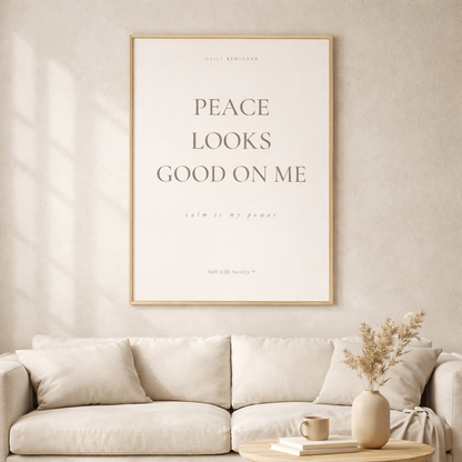 Framed artwork with 'Peace Looks Good on Me' text above a beige sofa in a living room.