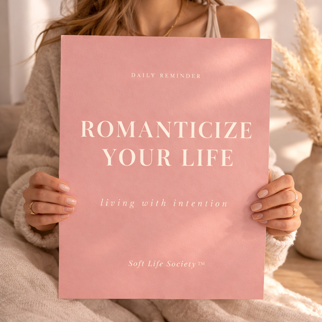 Person holding a pink book titled 'Romanticize Your Life' by Soft Life Society.