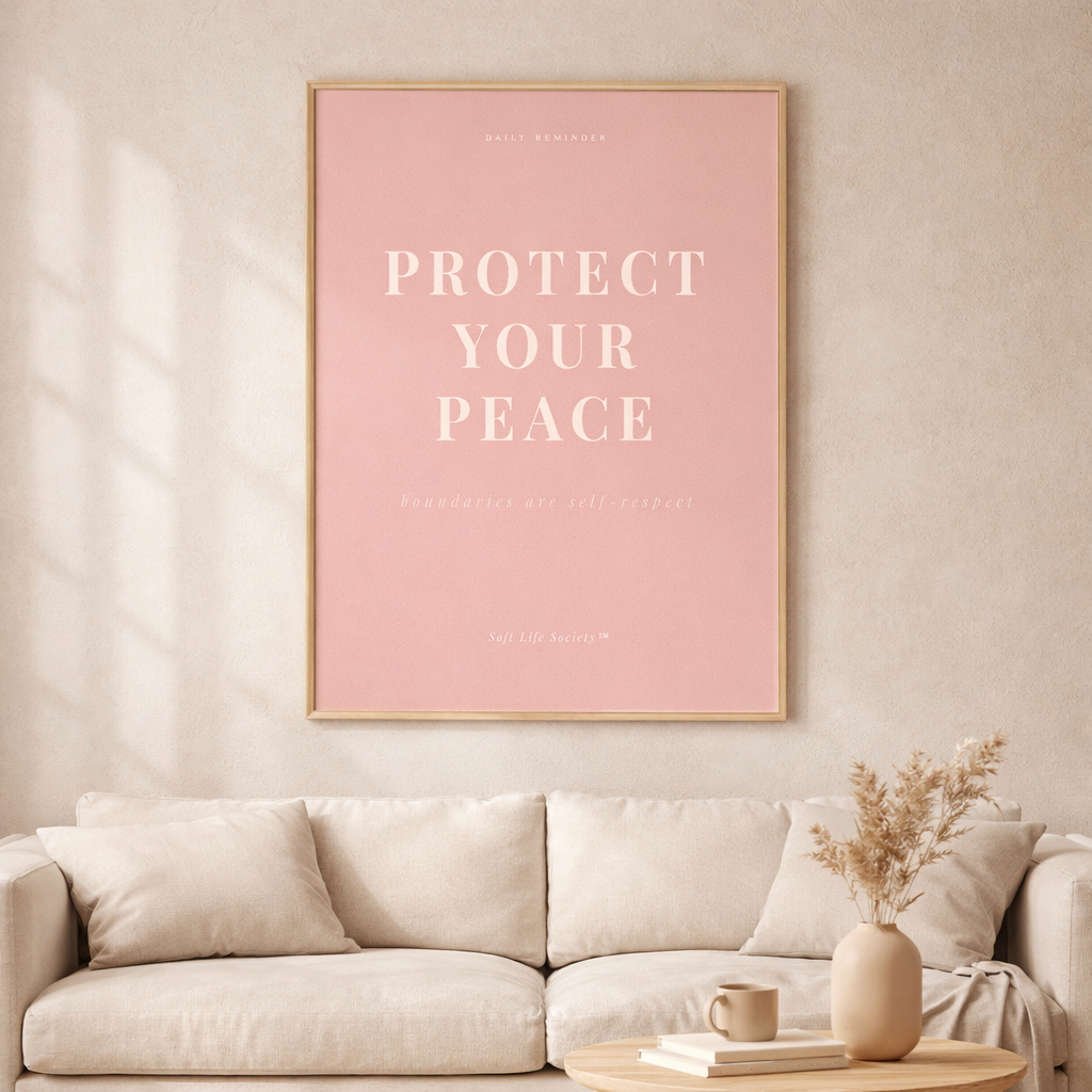 Pink framed poster with 'PROTECT YOUR PEACE' text on a wall above a beige sofa.