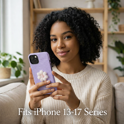 Woman holding a phone with a purple case featuring a white flower design, sitting on a couch in a cozy room.