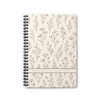 Notebook with floral pattern with banner reading "Romanticize Your Life" affirmation on a white background