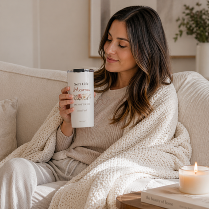 Woman relaxing on couch with Soft Life Mama tumbler, cozy self-care moment with candle, soft neutral home aesthetic
