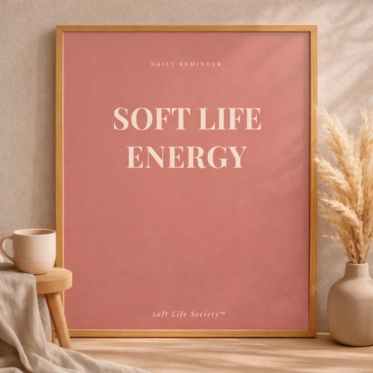 Framed poster with 'Soft Life Energy' text on a pink background, placed on a wooden surface with decorative elements.