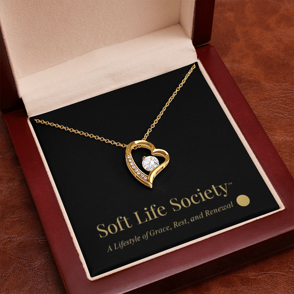 Close-up of gold Forever Love Necklace inside mahogany luxury box with branded message card.