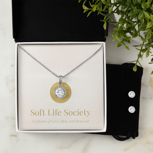 Soft Life Society solitaire pendant necklace with halo setting and matching stud earrings displayed in branded gift box.