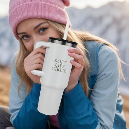 Woman holding a white Soft Life Girlie™ 40oz insulated tumbler with handle and straw while sitting outdoors in cool weather.