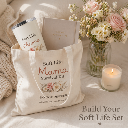 Tote bag labeled 'Soft Life Mama Survival Kit' with a mug, book, and flowers on a soft surface.