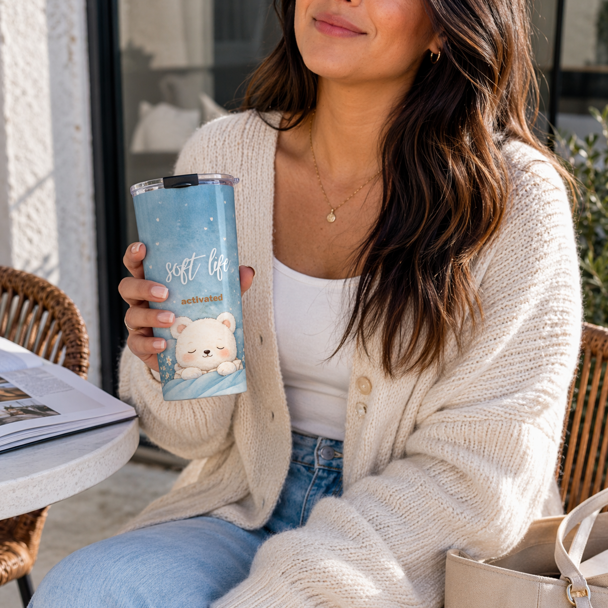 Woman holding a 'soft life' tumbler with a bear design outdoors.