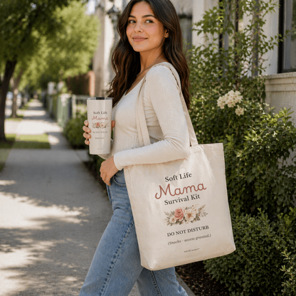 Woman holding a tote bag and a mug with 'Soft Life Mama' branding outdoors.